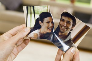 Hands ripping photograph of couple
